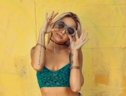 Una mujer tatuada con un top corto audaz y gafas de sol.