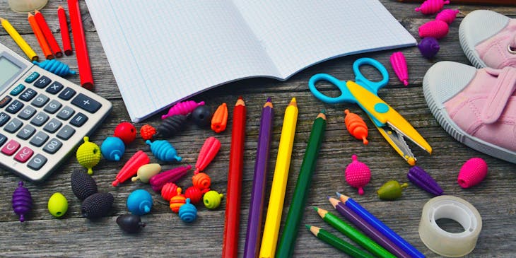 Des fournitures scolaires colorées sont disposées sur un bureau.