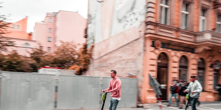 People riding scooters down a street.