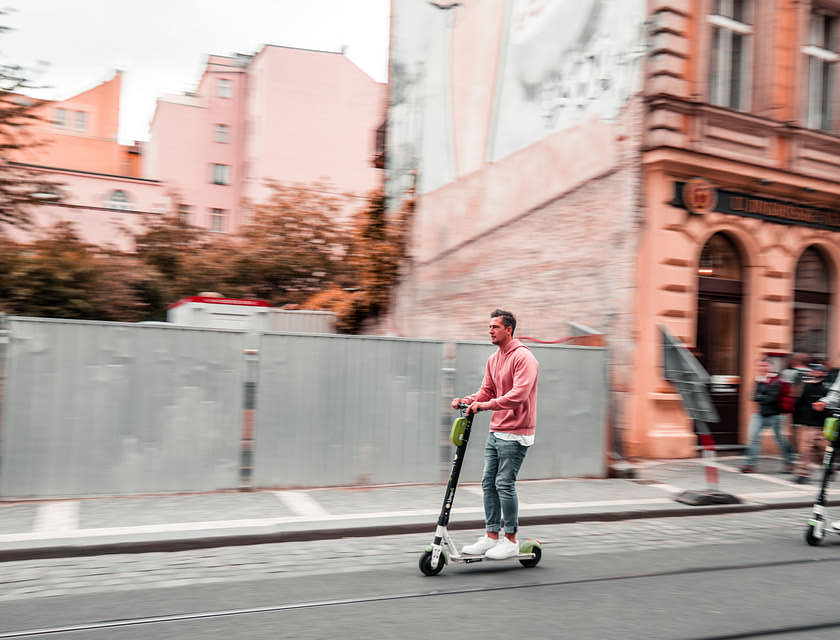 People riding scooters down a street.