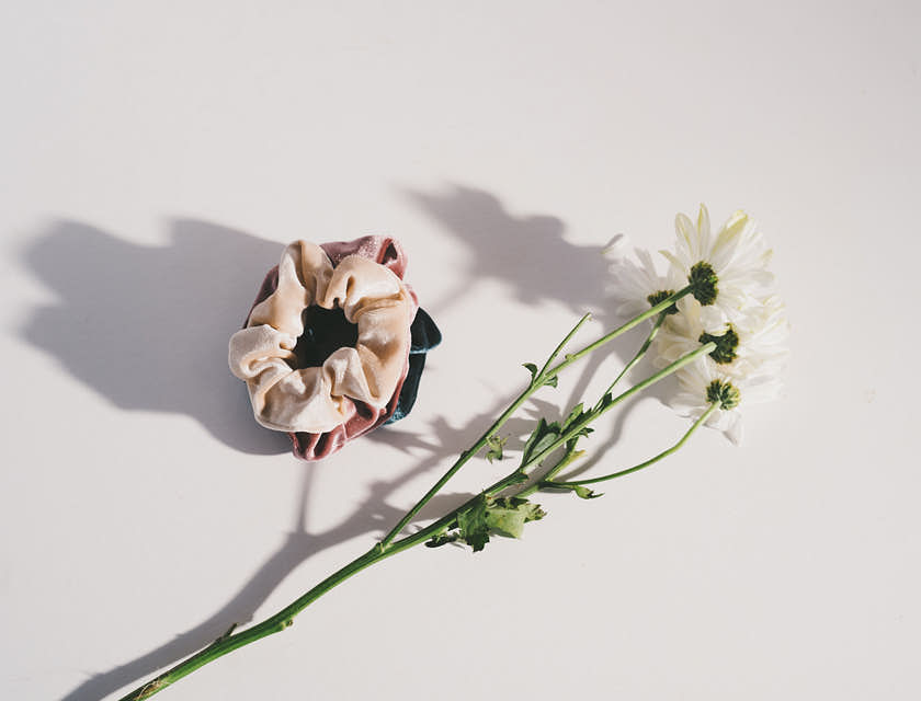 Alcuni elastici per capelli sopra un tavolo con accanto un fiore.