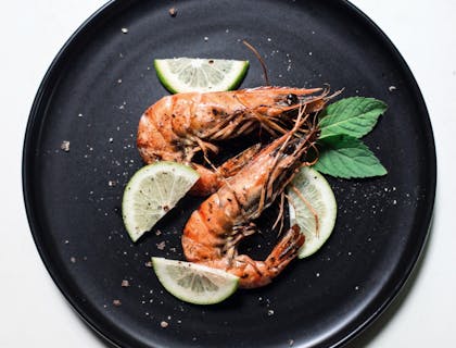 Due gamberi guarniti con foglie di basilico e fette di limone in una cucina di pesce di un ristorante di pesce.