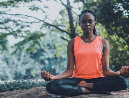 Una donna che si prende cura di se stessa facendo meditazione e yoga all'aria aperta.