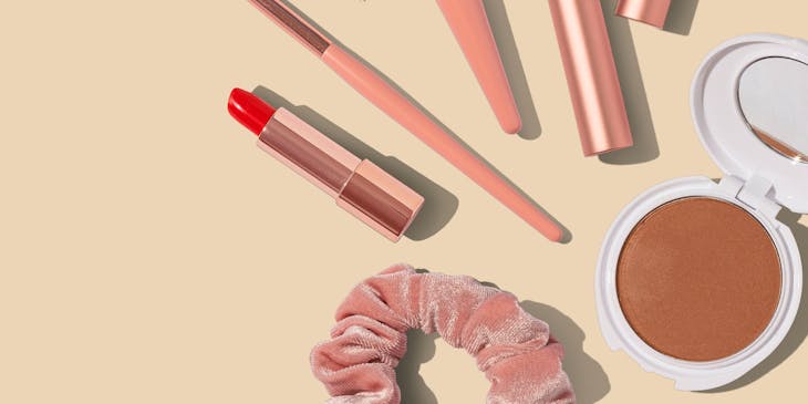 Makeup products on a pink surface.