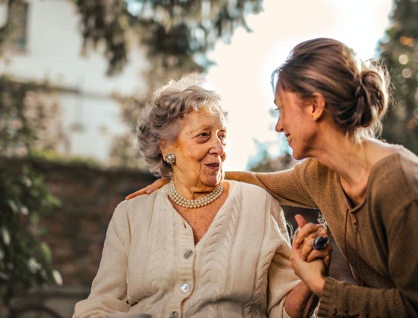 Funcionária de uma agência de cuidadores de idosos conversando com uma paciente.