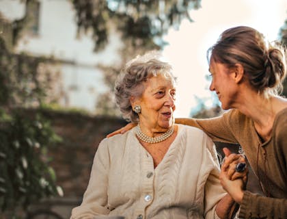 Una volontaria di un servizio di aiuto per anziani che sorride ad una signora mentre le fa compagnia.