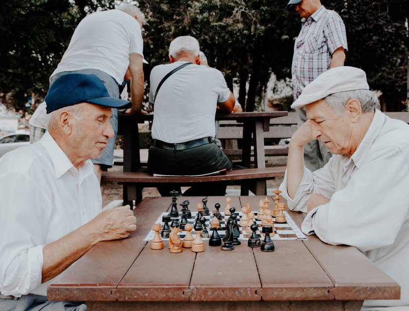 Deux personnes âgées en train de jouer aux échecs dans le parc.