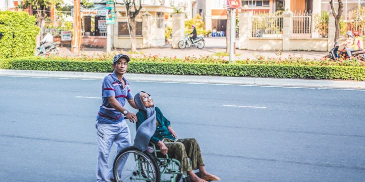Man pushing an elderly woman in a wheelchair.
