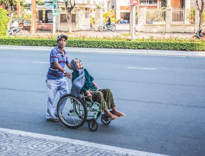 Hombre empujando a una anciana en silla de ruedas en un negocio de transporte para personas mayores.