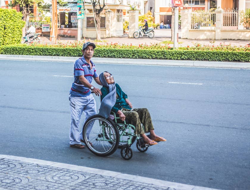 Man pushing an elderly woman in a wheelchair.