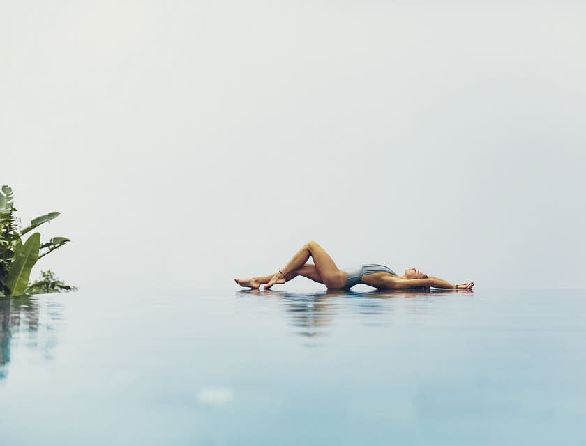 una mujer acostada y posando a un lado de una alberca infinita en un negocio sensual