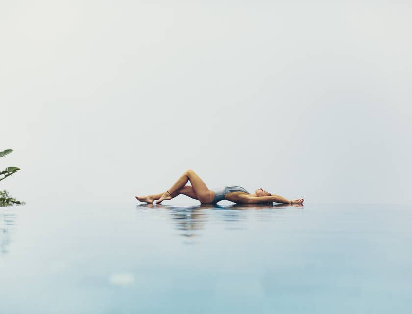 Una donna sdraiata in modo sensuale a bordo piscina.