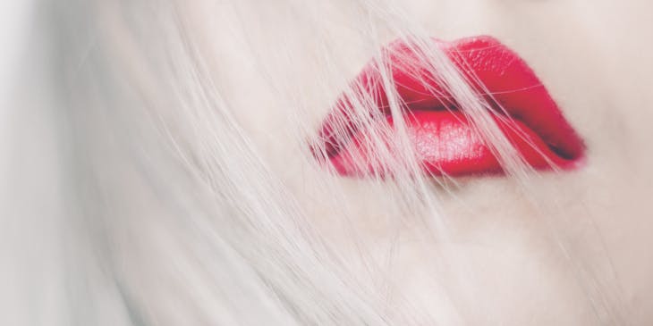 Blond hair blowing over red lips