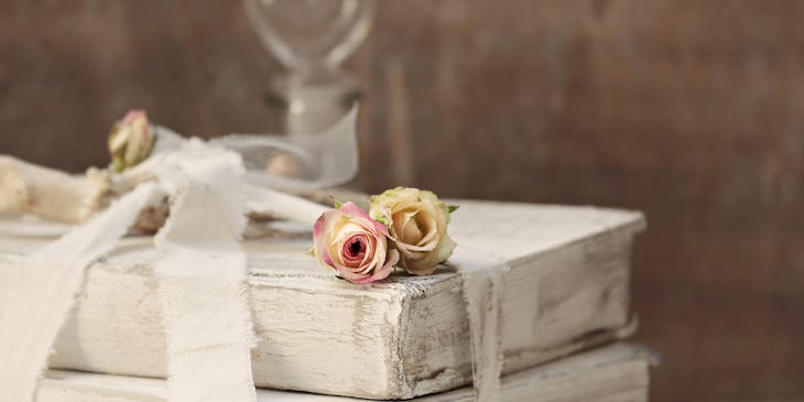 Dried flowers on old books tied up with white ribbon.