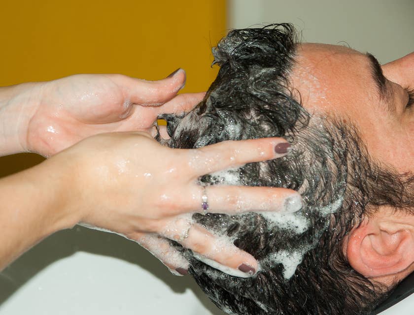 Un homme qui se fait laver les cheveux avec du shampooing.