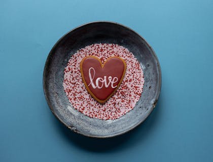 The short word "love" written across a sweet cookie surrounded by sprinkles.