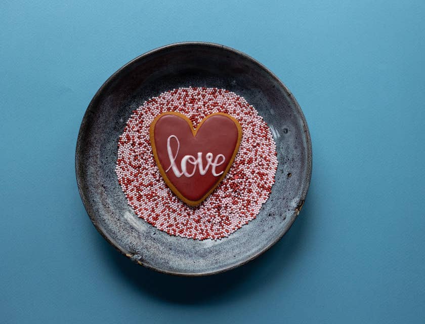 The short word "love" written across a sweet cookie surrounded by sprinkles.