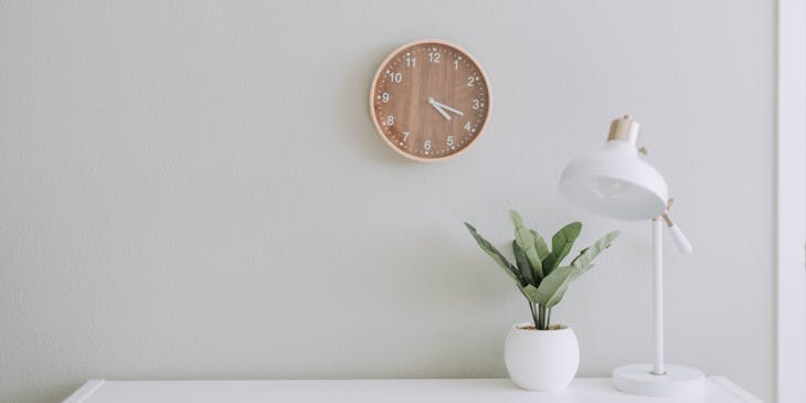Une simple lampe et une plante sur un bureau blanc.
