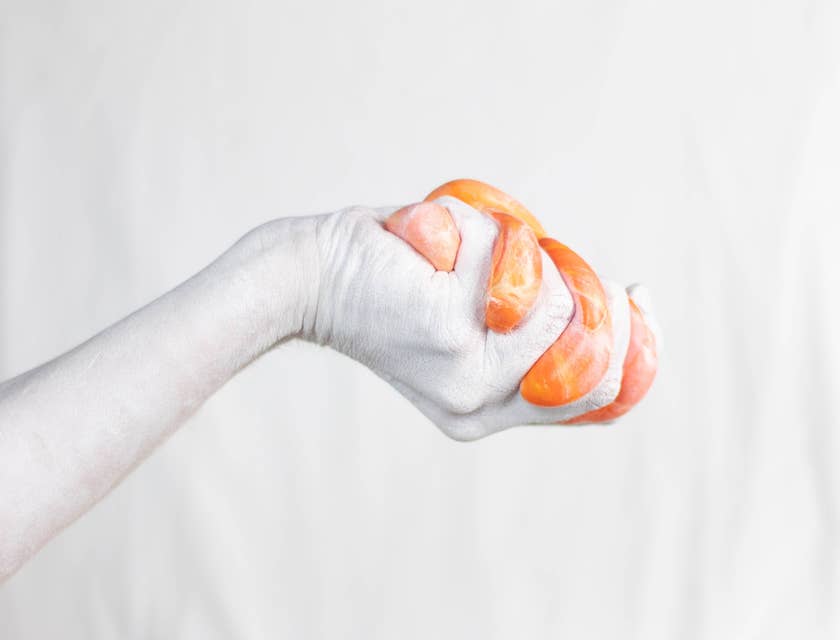 Una mano che stringe dello slime arancione.