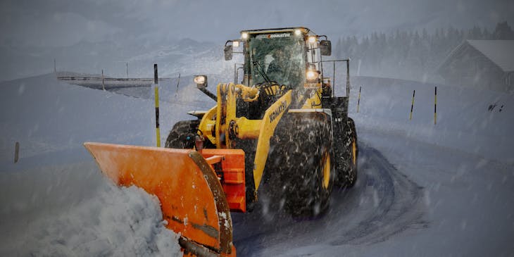 A plow removing snow from a mountain road.