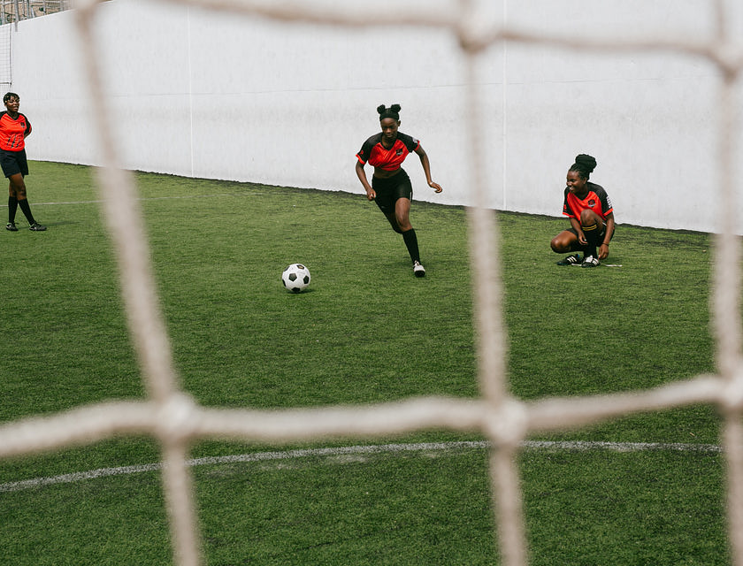 Des filles en maillots rouges et noirs jouant au football.