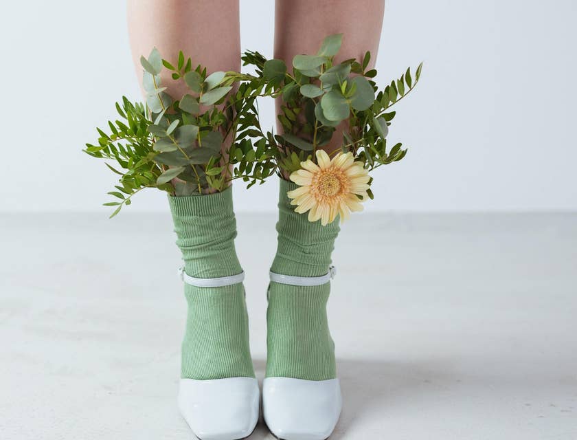Uma menina usando meias e salto alto com algumas flores dentro das meias.