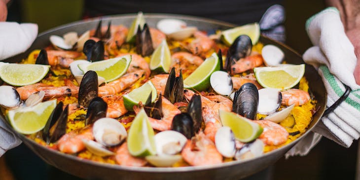 Seafood paella garnished with sliced lime.