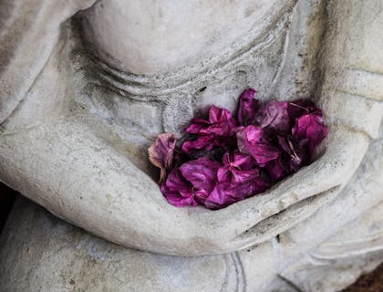 Des fleurs violettes dans les bras d'une statue.