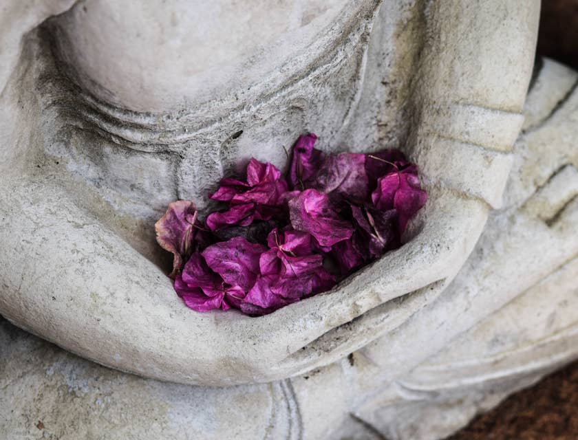 Purple flowers held on a statue's lap.