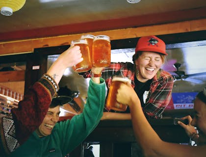 gente celebrando con tarros de cerveza en un bar deportivo