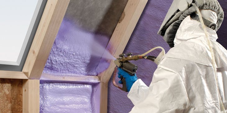 person applying spray foam to roof panels
