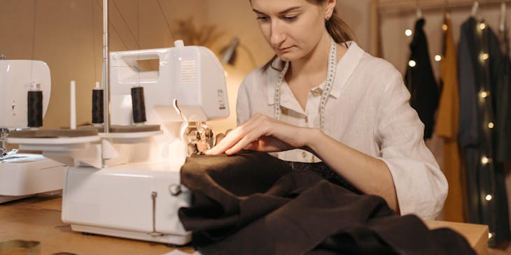 A tailor stitching a garment with a sewing machine.