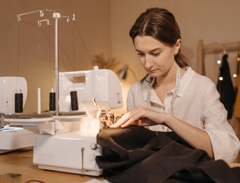 Alfaiate costurando uma peça de roupa com uma máquina de costura.