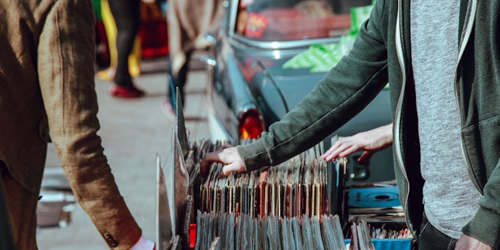 Shoppers browsing through vinyl records on the side of the street at a street vendor business.