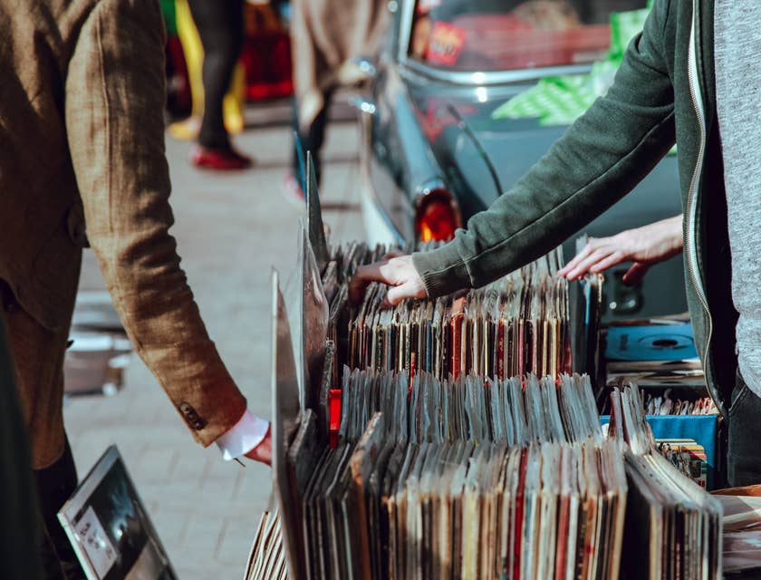 Compradores mirando discos de vinilo al lado de la calle en un negocio de vendedores ambulantes.