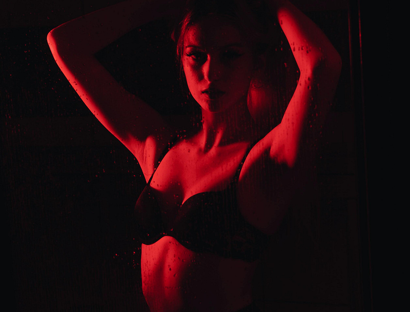 Mujer en una pose cachonda mientras está iluminada por una luz roja.