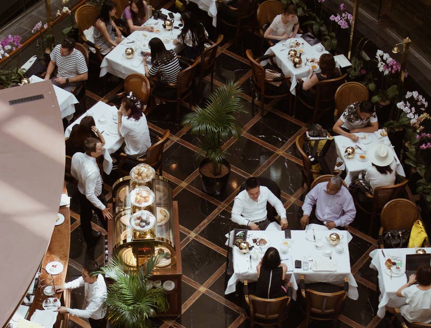 Gäste sitzen während eines kulinarischen Events an weißen Tischen.