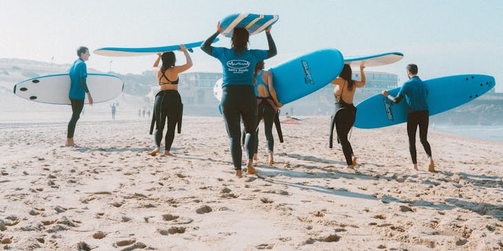 Group of surfers in wet suits carrying their surf boards.