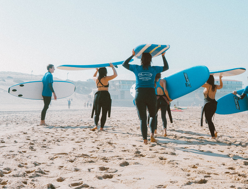 Group of surfers in wet suits carrying their surf boards.