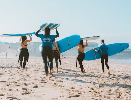 Group of surfers in wet suits carrying their surf boards.