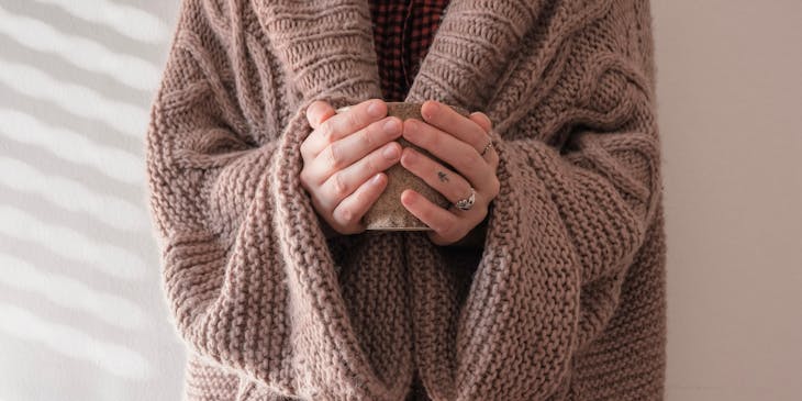 A person wearing a beige sweater from a sweater business.