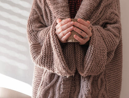 A person wearing a beige sweater from a sweater business.