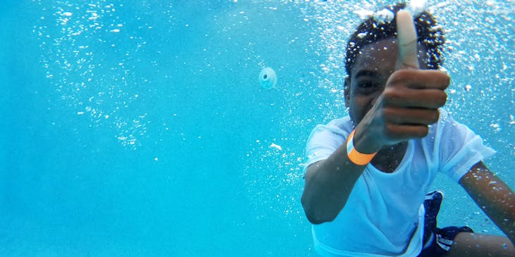 A boy gives thumbs up while learning to swim at a swimming school business.