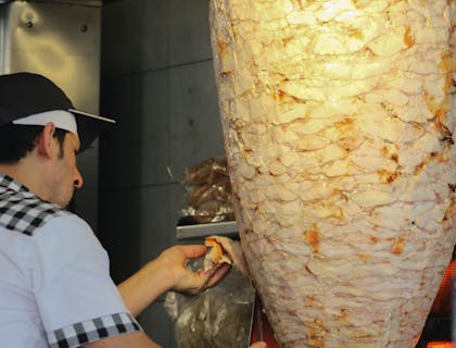 Hombre preparando shawarma en un negocio de restaurante sirio