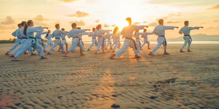 People practicing Tai Chi on a beach.