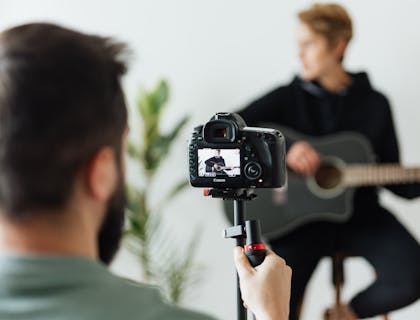 Un hombre grabando a un músico tocando la guitarra en una agencia de talentos.
