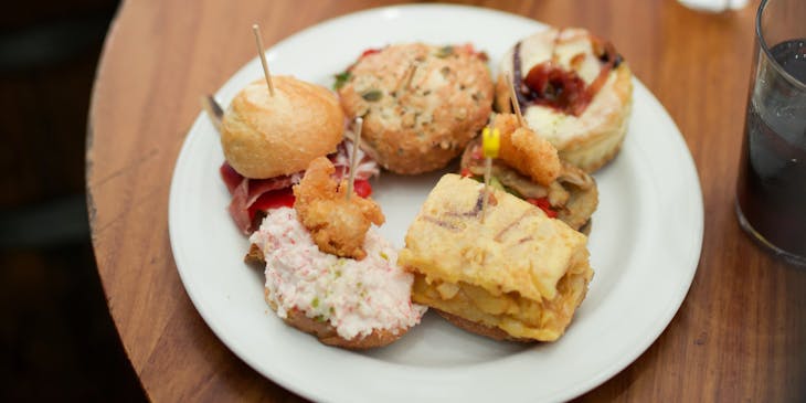 Two plates of tapas served with drinks.