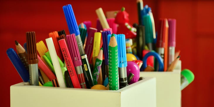Holder full of different colored pens and pencils at a teacher supplies store.