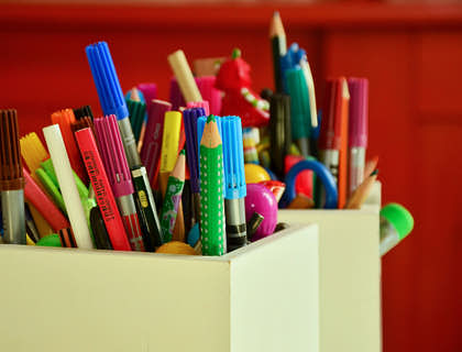 Due portapenne pieni di matite colorate e penne comprate da un'azienda di materiale per insegnanti.