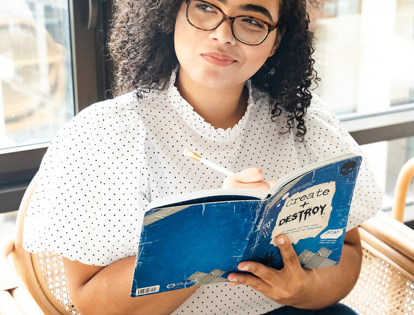 Une femme qui prend des notes dans son livre, l'air prévenant.